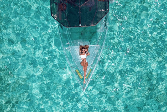 Mujer acostada en una lancha transparente en el mar